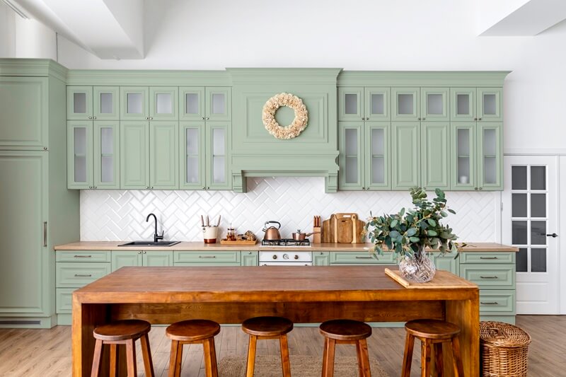 A kitchen with pastel cabinets and a vintage backsplash