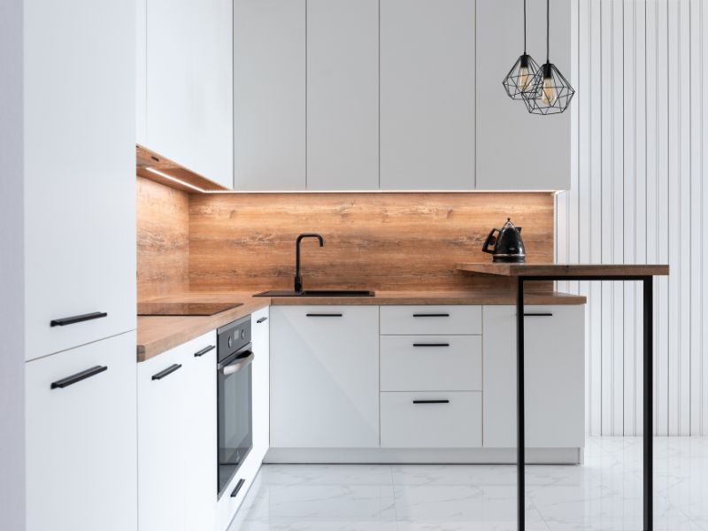 A modern small kitchen with vertical shelving, compact appliances, and natural light streaming through a window