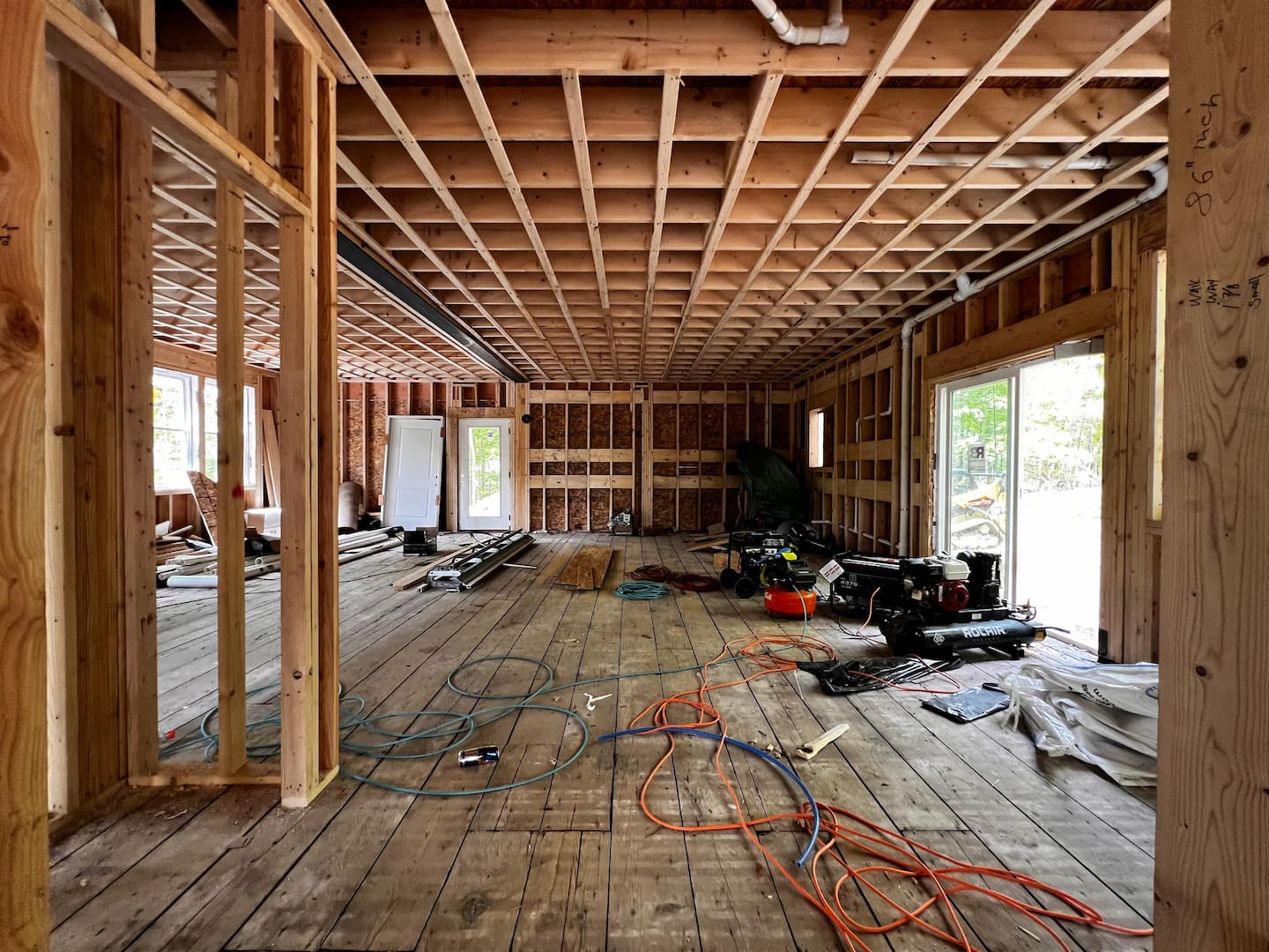 Interior view of a room with wood framing and construction tools, highlighting new home additions in progress.