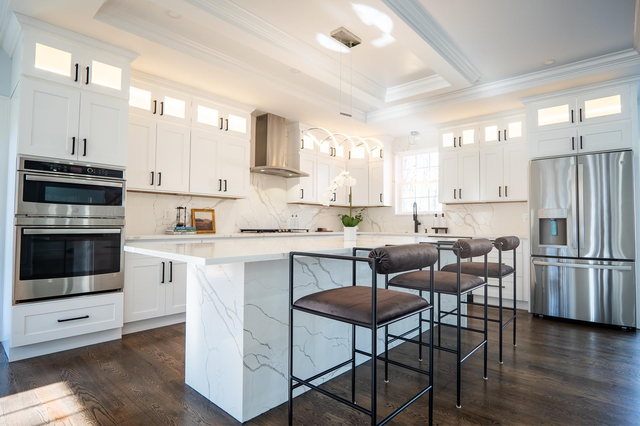 Pristine white kitchen designed by residential architects in Boston, MA using polished stainless steel appliances, embodying a stylish and functional design.