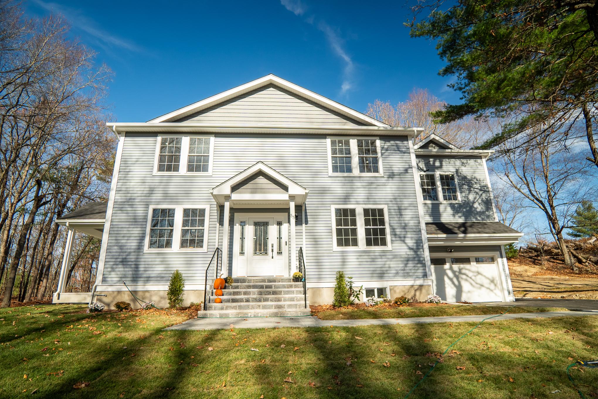 A new home designed by local residential architects with an inviting front porch and a neat driveway, expert exterior design.