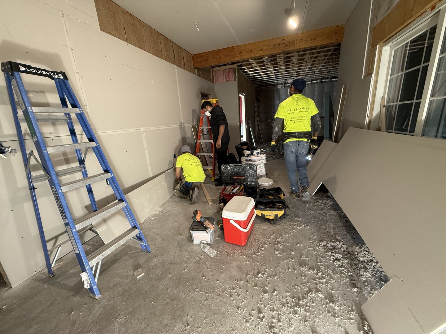 Three contractors inspecting the drywall they just installed during a house remodeling project.