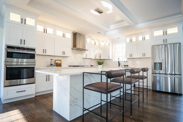 Bright white kitchen designed with polished stainless steel appliances, embodying a stylish and functional design.