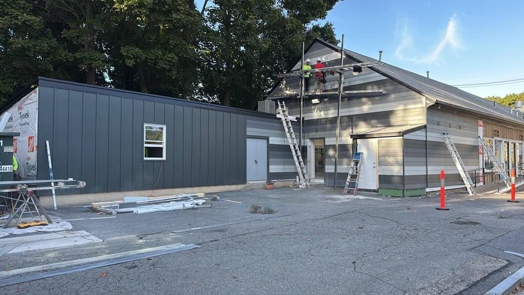 Two contractors installing siding on a building