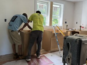Two contractors installing new cabinets during a kitchen renovation.